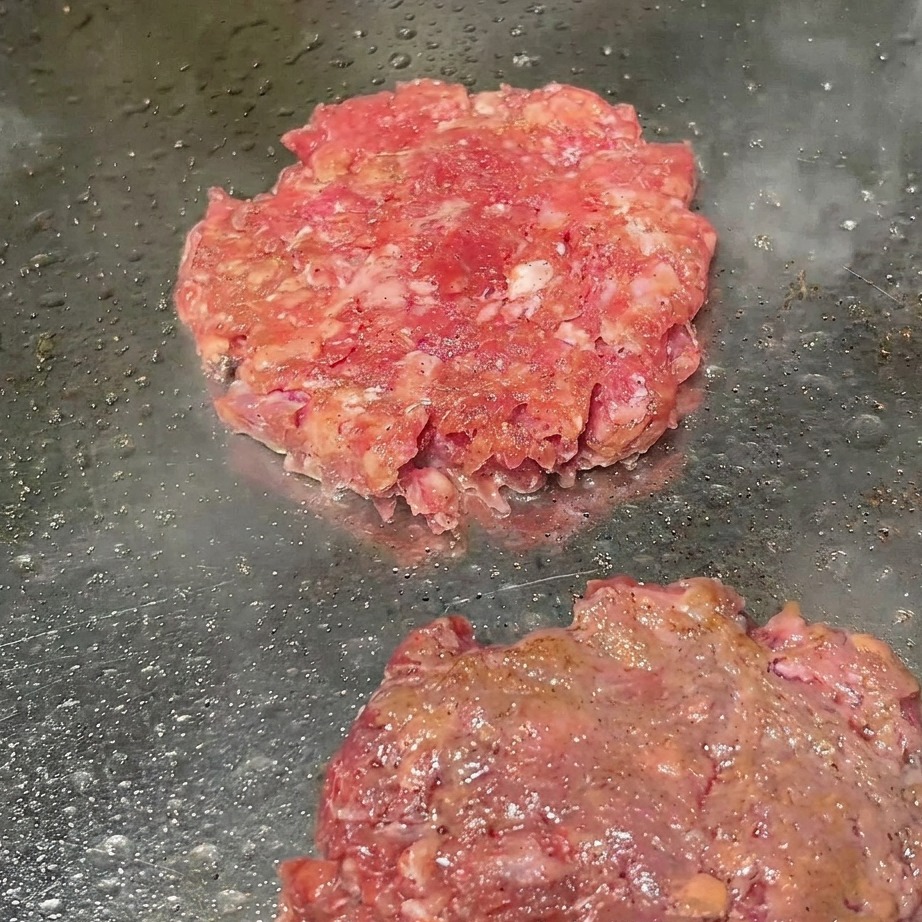 焼いているパティに黒胡椒を振る様子。