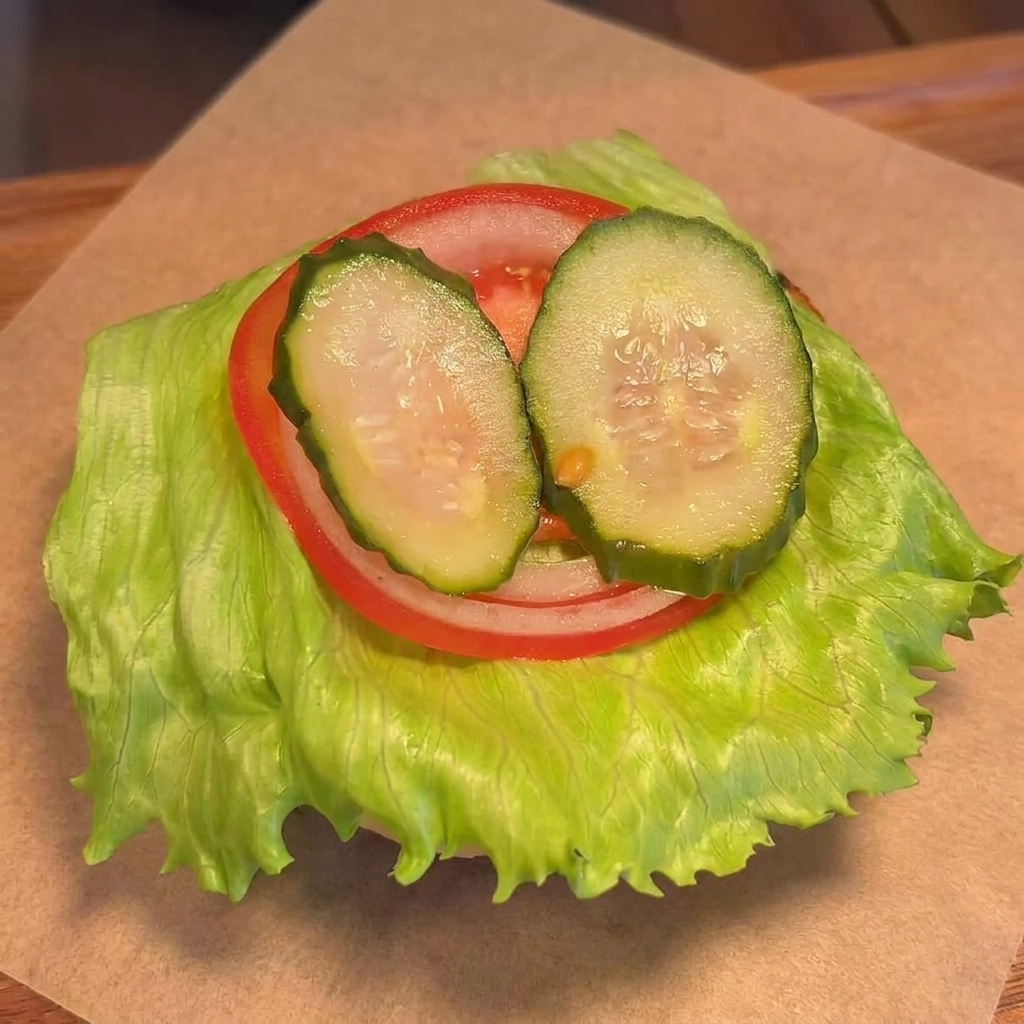 野菜を重ねたバンズの上に、チーズがのったパティを置く様子。