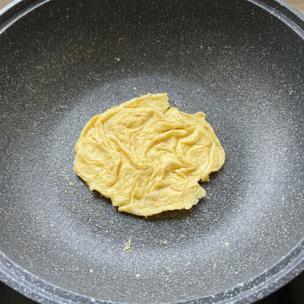フライパンの中で卵の上にとろりと溶け出したチーズ。