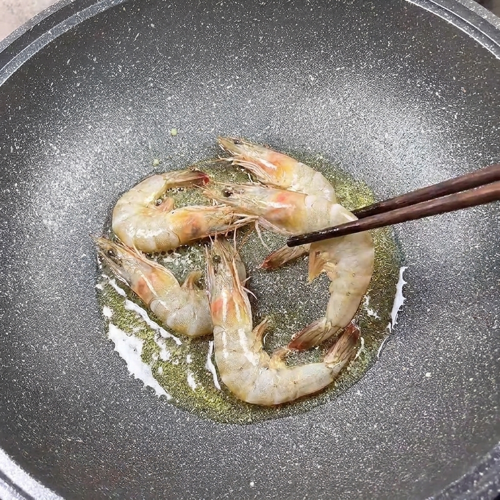 箸で裏返しながら焼かれている下味付きの海老。