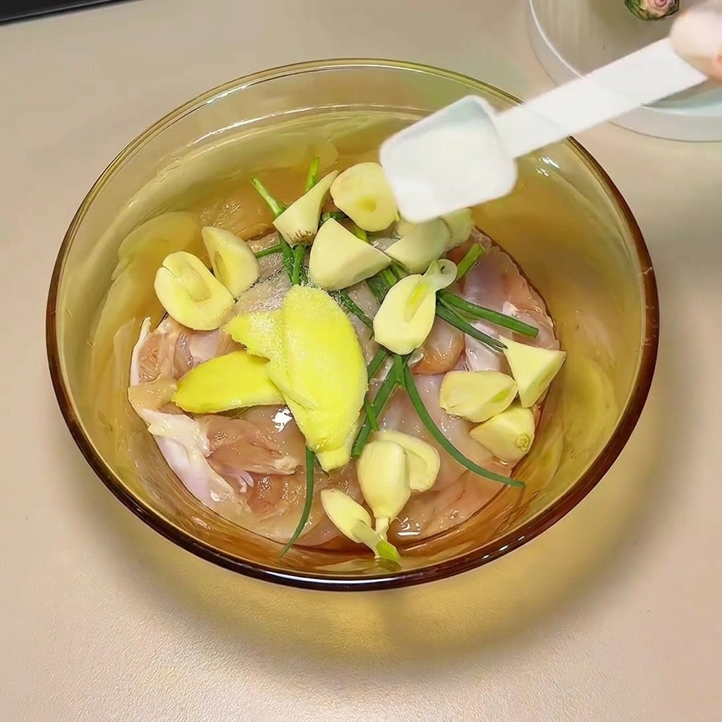 醤油とスパイスを鶏肉と香味野菜にかける様子。