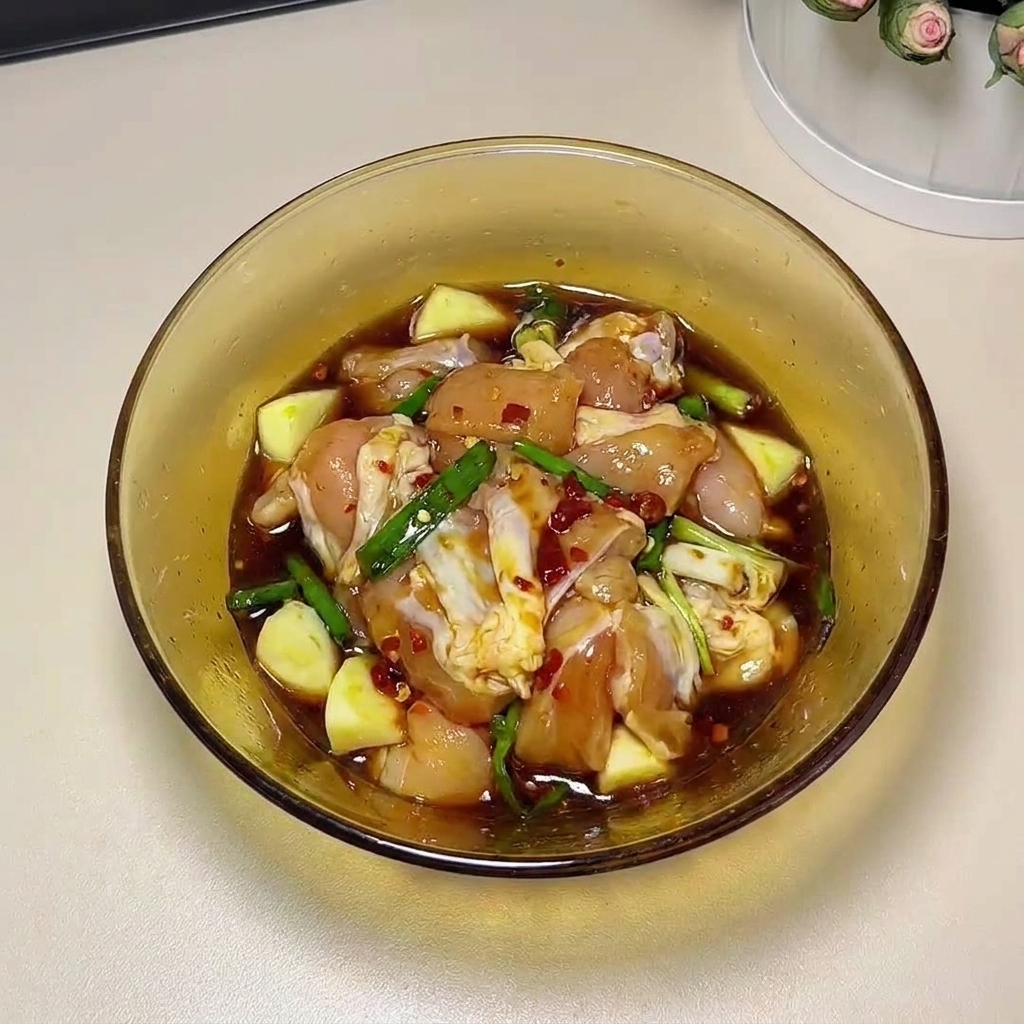 手袋をはめた手でマリネ液を鶏肉に揉み込む様子。