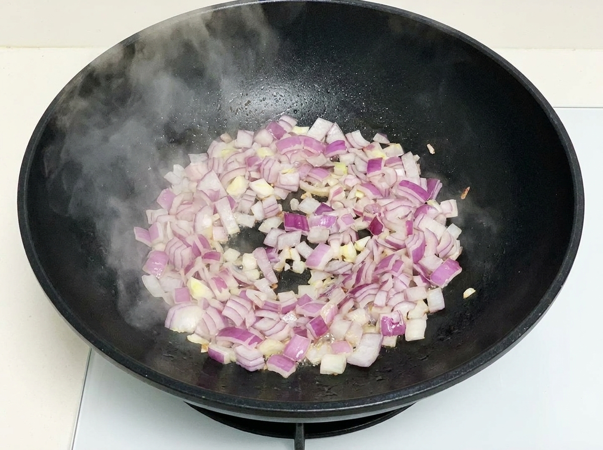中華鍋で紫玉ねぎを炒める様子。