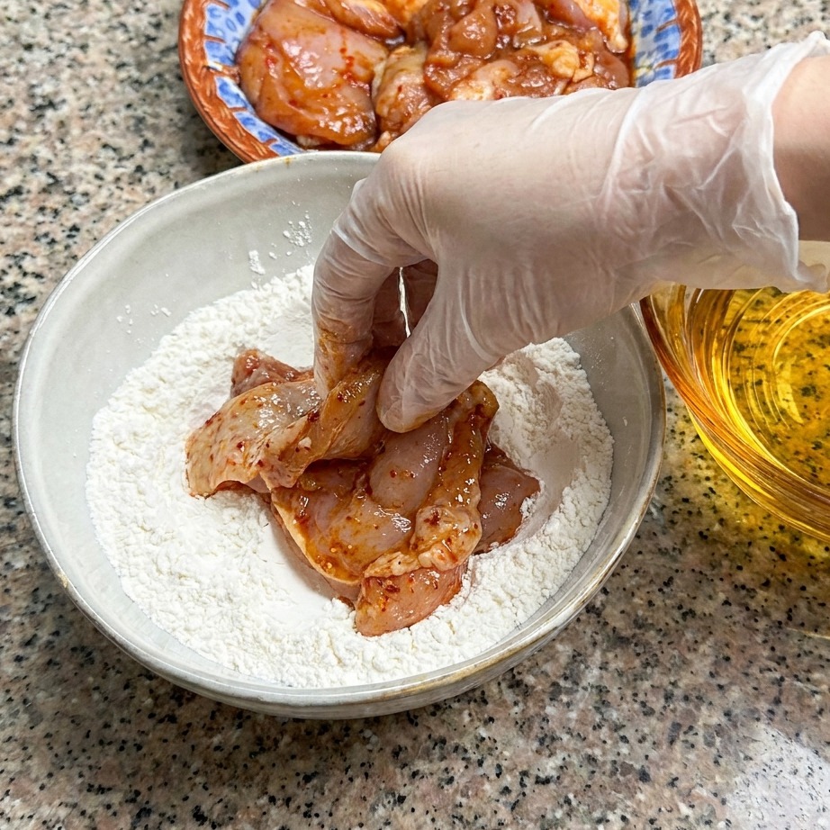 下味をつけた鶏肉に小麦粉をまぶす様子。