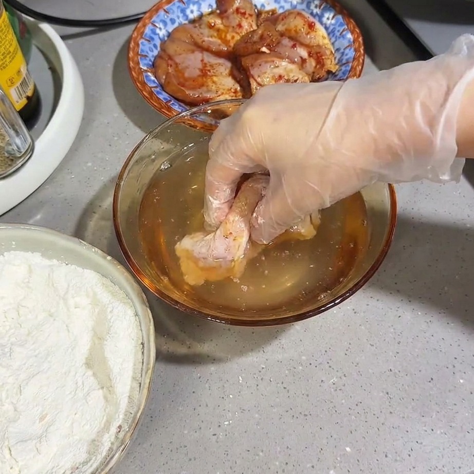粉をつけた鶏肉を水にさっとつける様子。