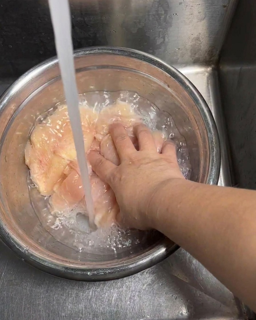ボウルに入った鶏肉を冷水でしっかりすすいでいる様子。