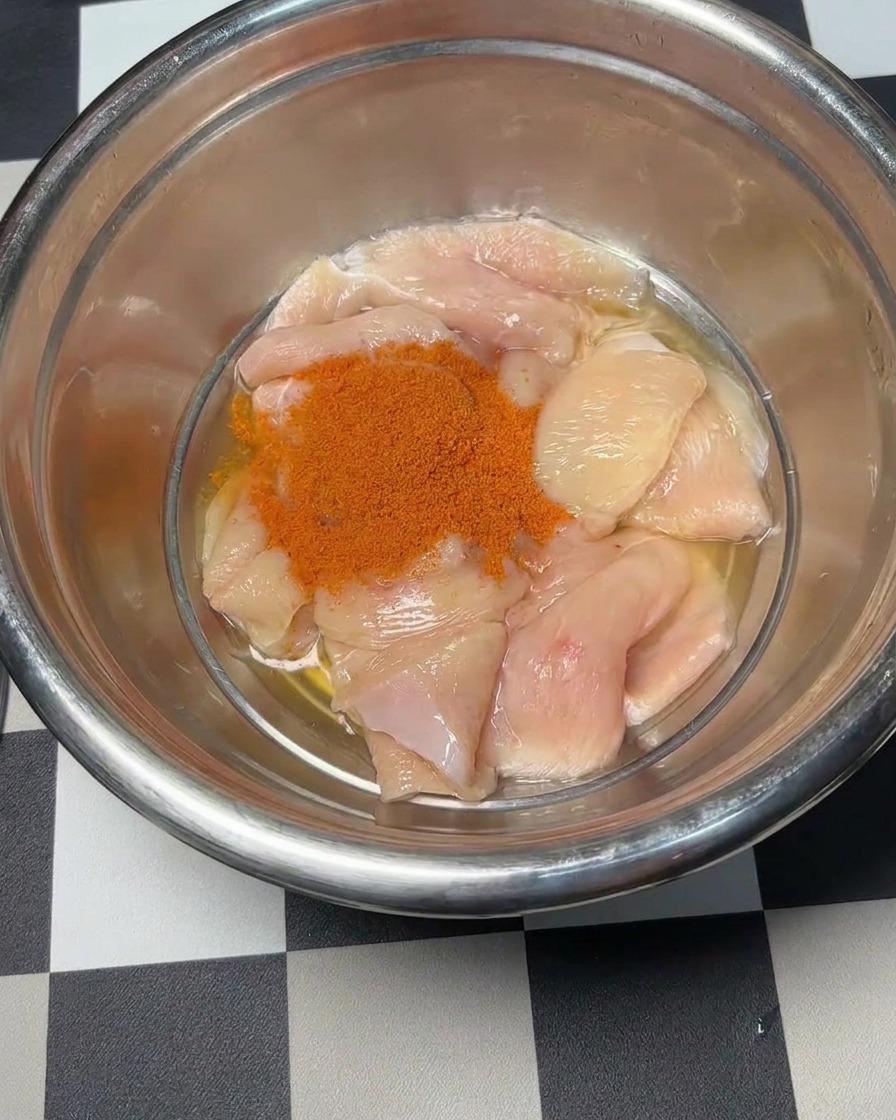 水気を切った鶏肉に赤いオーリンズパウダーをかけている様子。