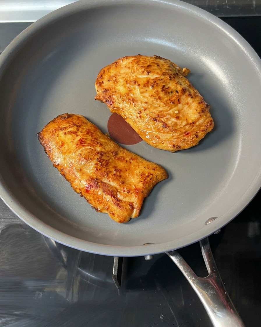焼き上がったチキンをフライパンから取り出している様子。
