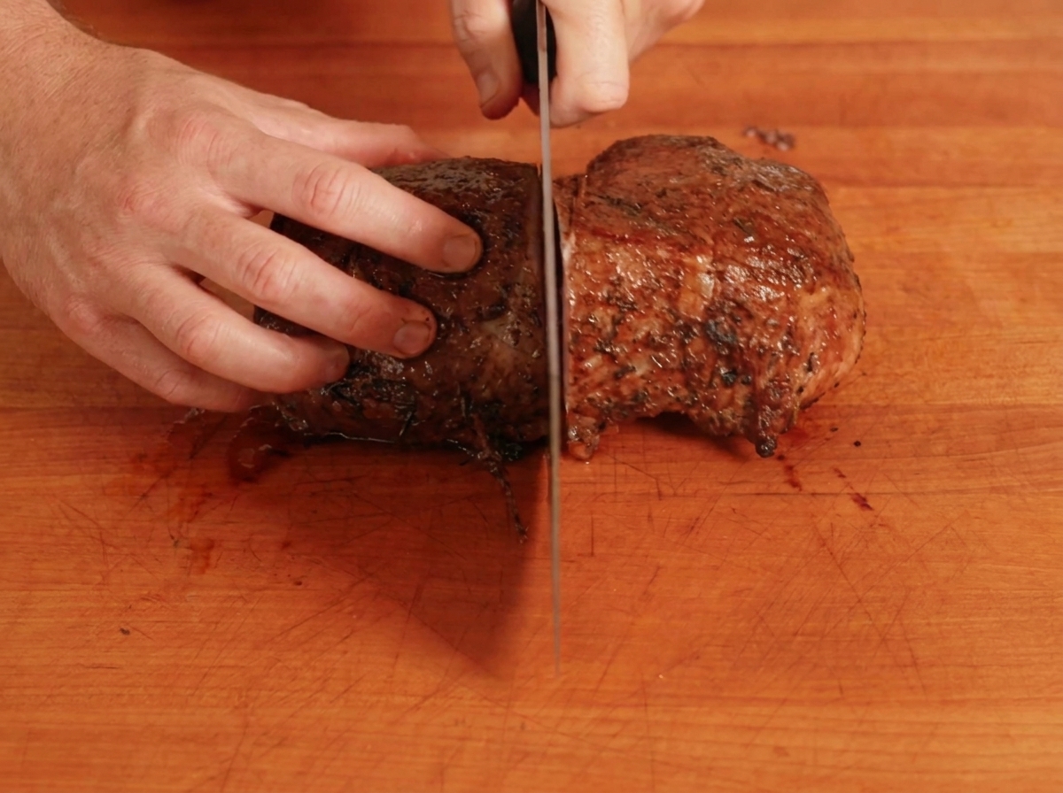 調理した牛肉をまな板で半分に切っている様子。