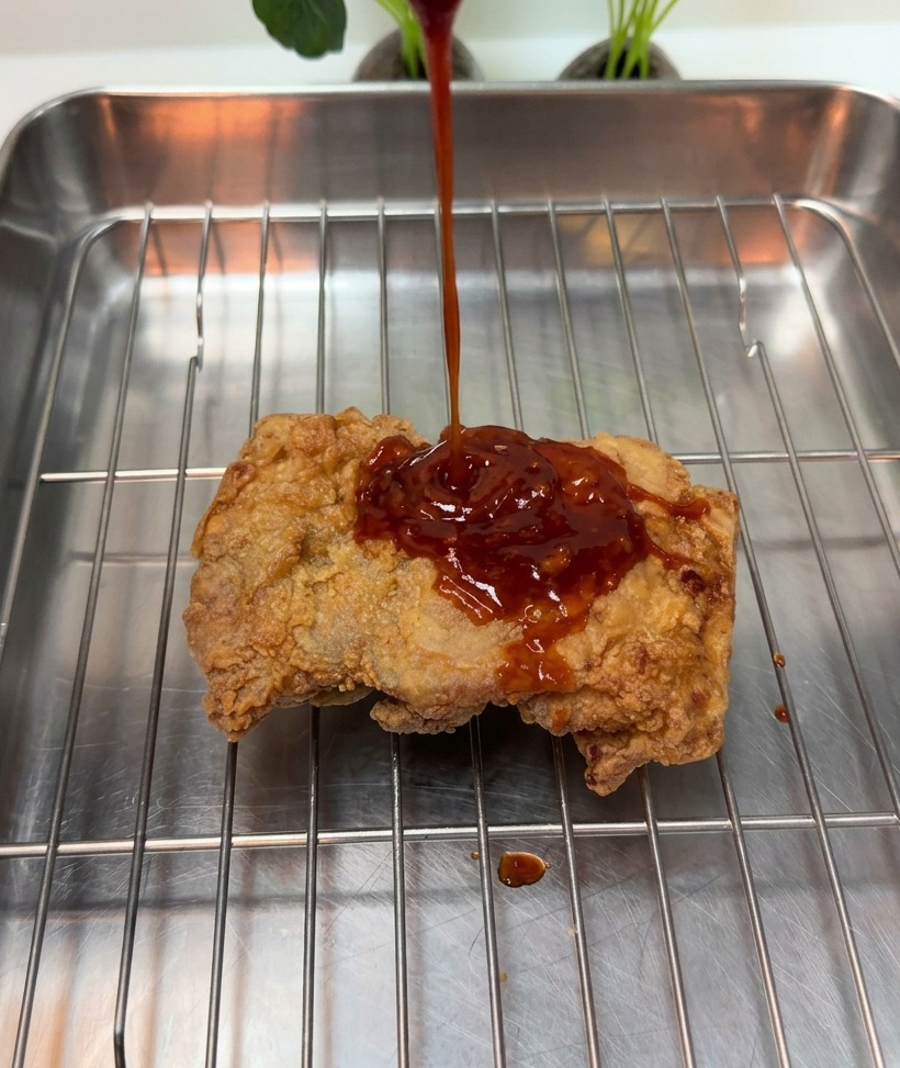 ワイヤーラックの上のチキンにソースをかける様子