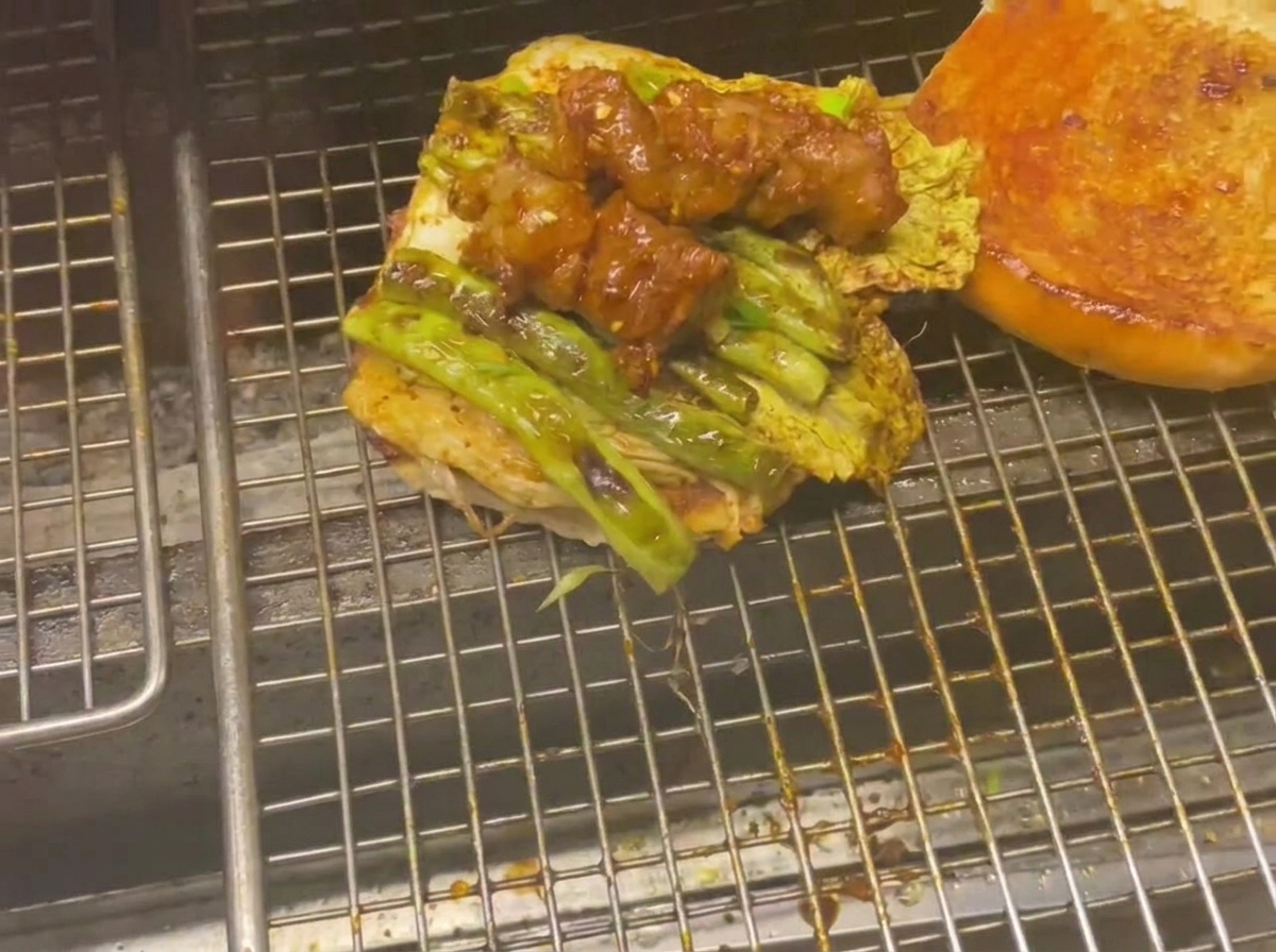 バンズの上に野菜と肉が重ねられていく様子。