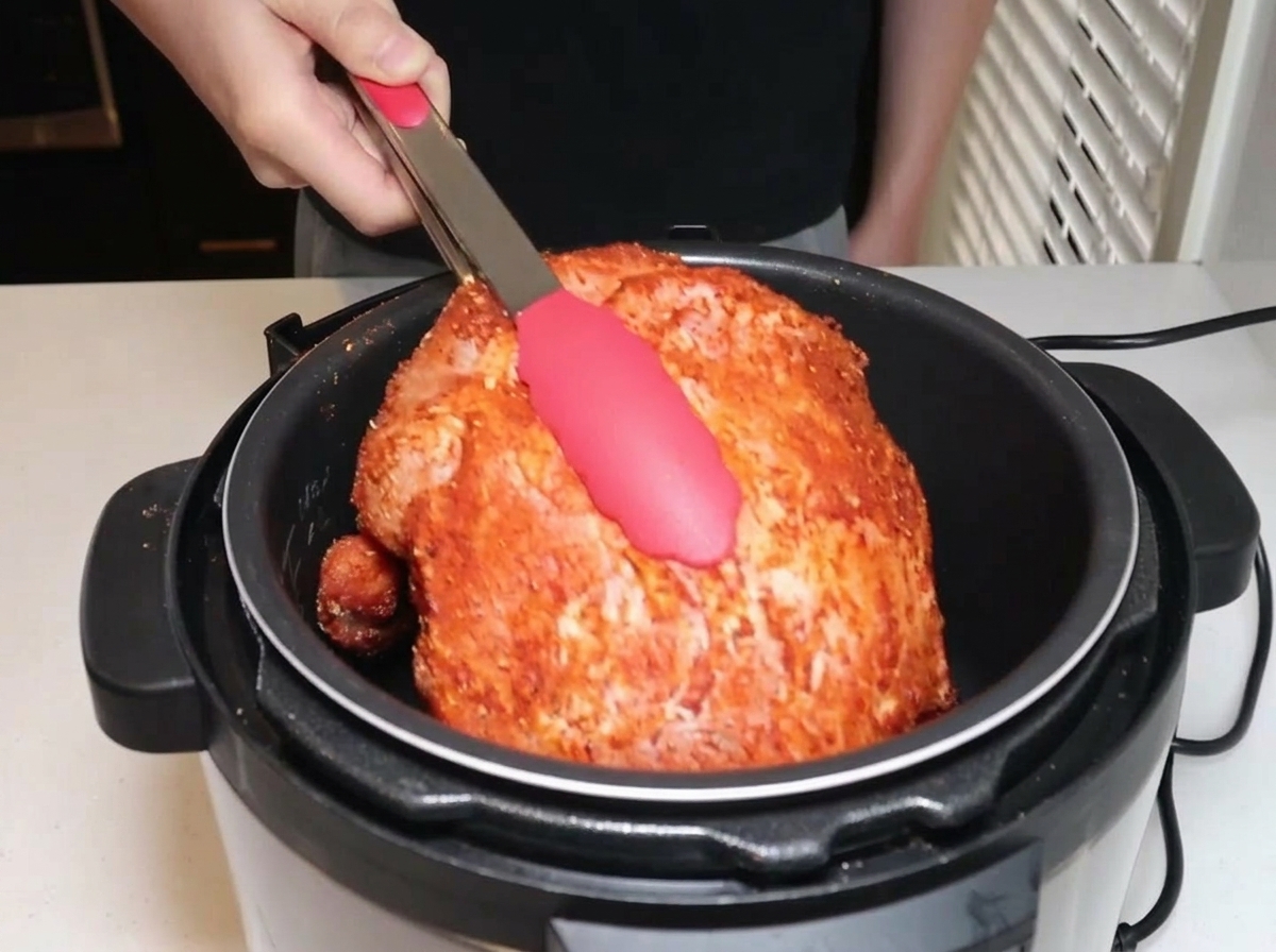 トングを使って味付けした豚肉を電気圧力鍋に入れている様子。