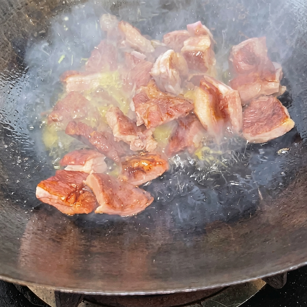 中華鍋の中でカラメルソースが絡んだスペアリブを炒めている様子。