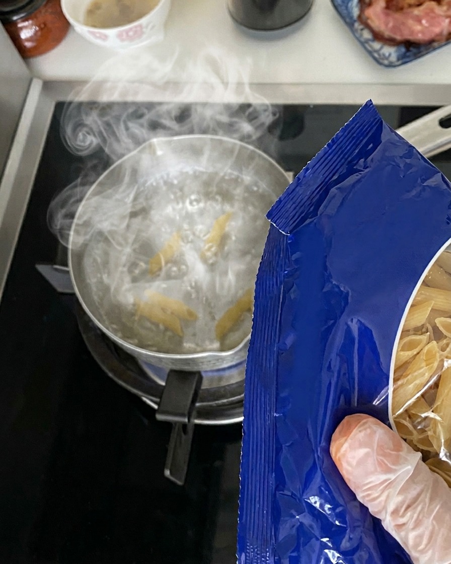 沸騰した鍋にペンネを投入している様子。