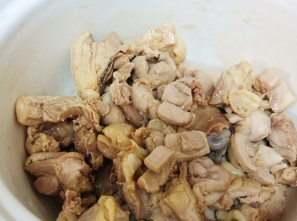 下茹でした鶏肉が白い土鍋の中に入っている様子。