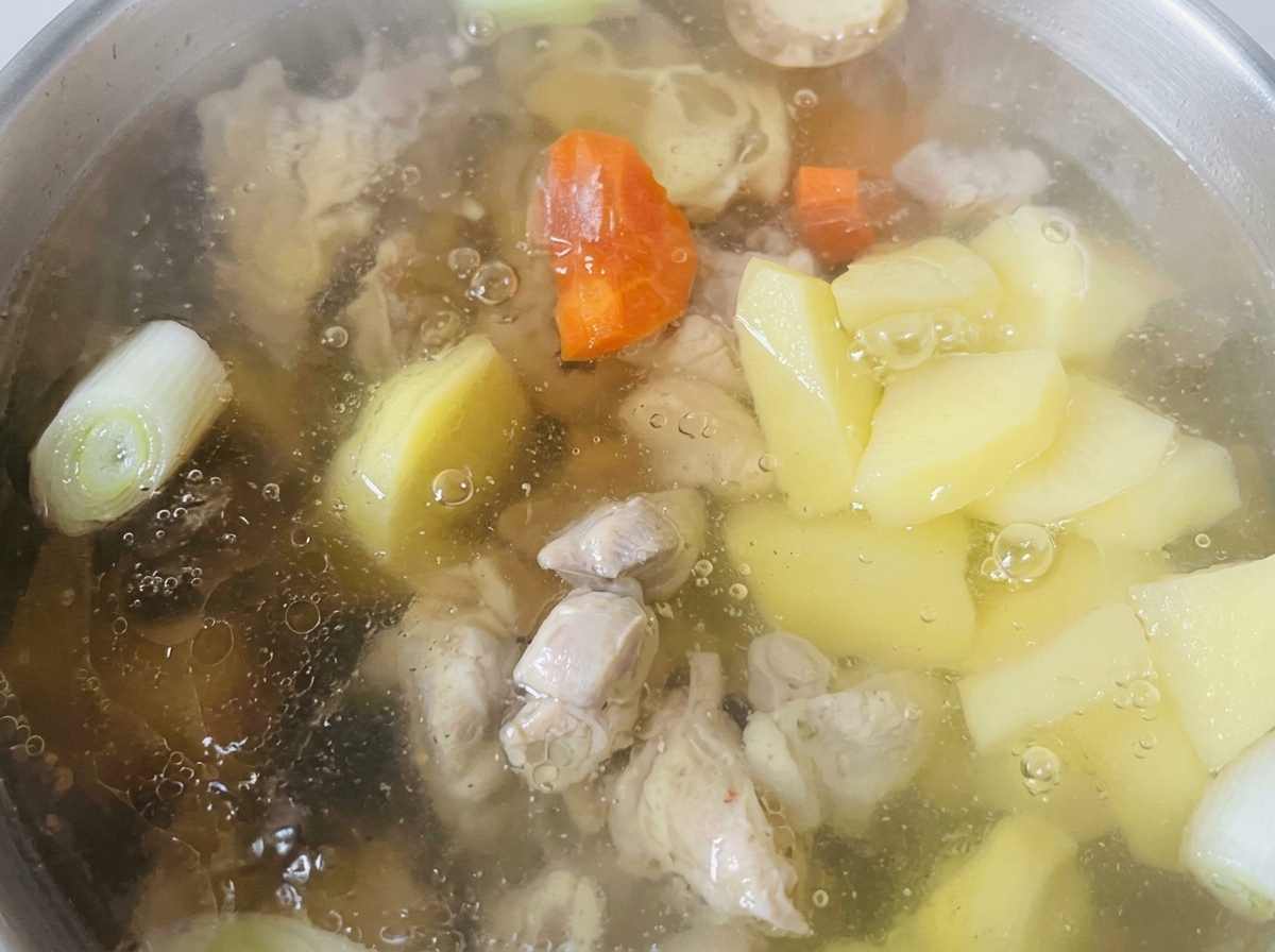 クリアなスープの中で鶏肉と一緒に煮込まれる、にんじんとじゃがいもの様子。