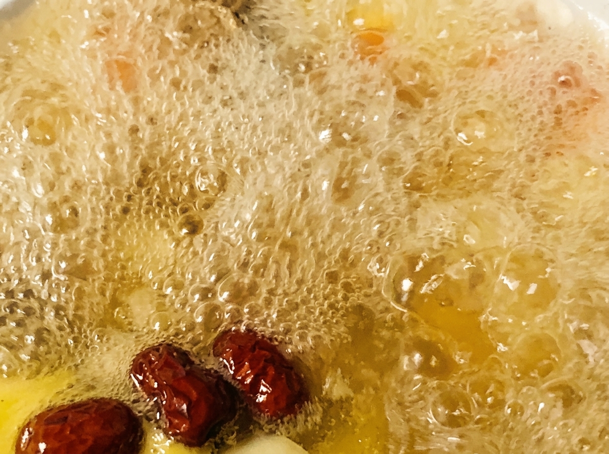 ぐつぐつと煮え立つ鶏スープにナツメと調味料を加えている様子。