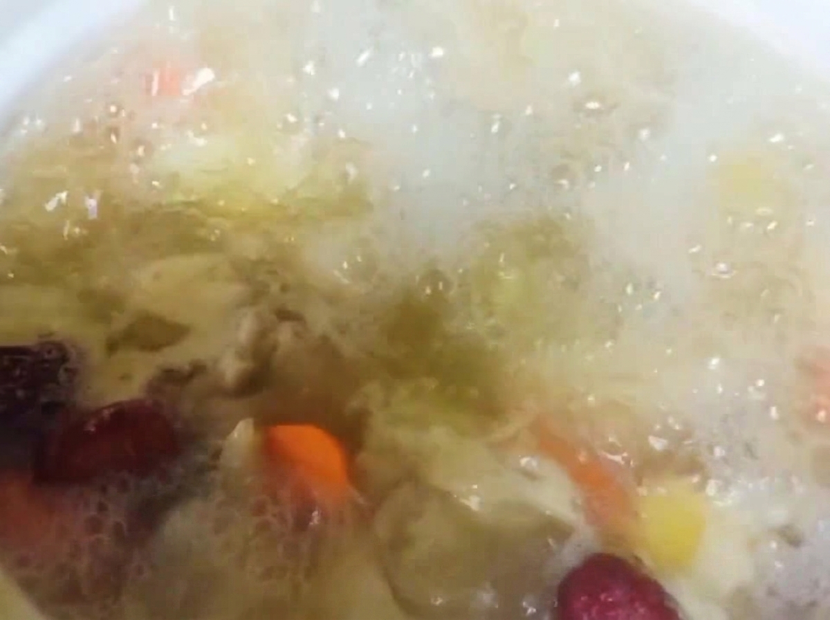 煮込んでいる鶏肉と野菜のスープに花椒(ホアジャオ)を加えている様子。