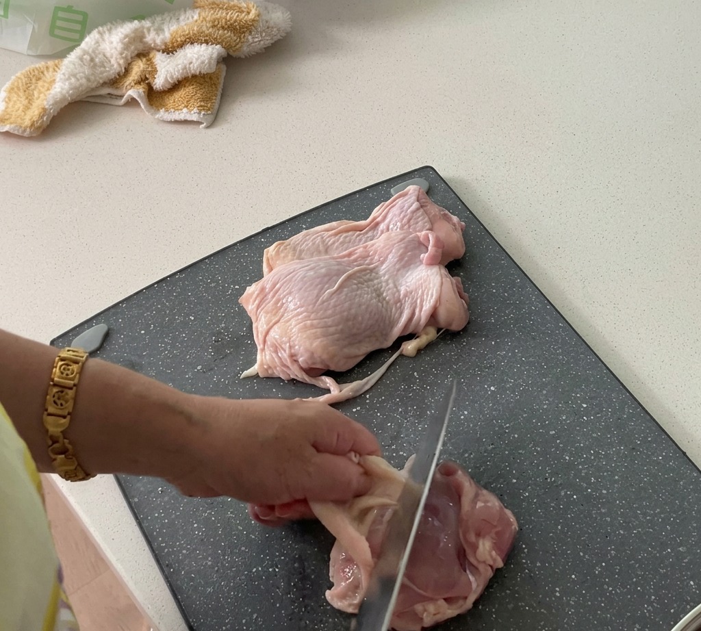 鶏もも肉の皮を剥ぎ、一口サイズにカットする準備をしている様子。