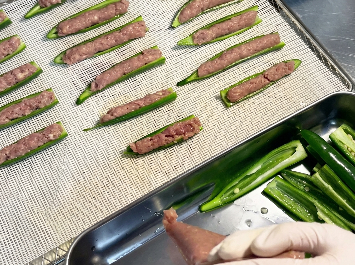 白いプラスチック製のメッシュトレイに、きれいに並べられた詰め物入りの生オクラボート。