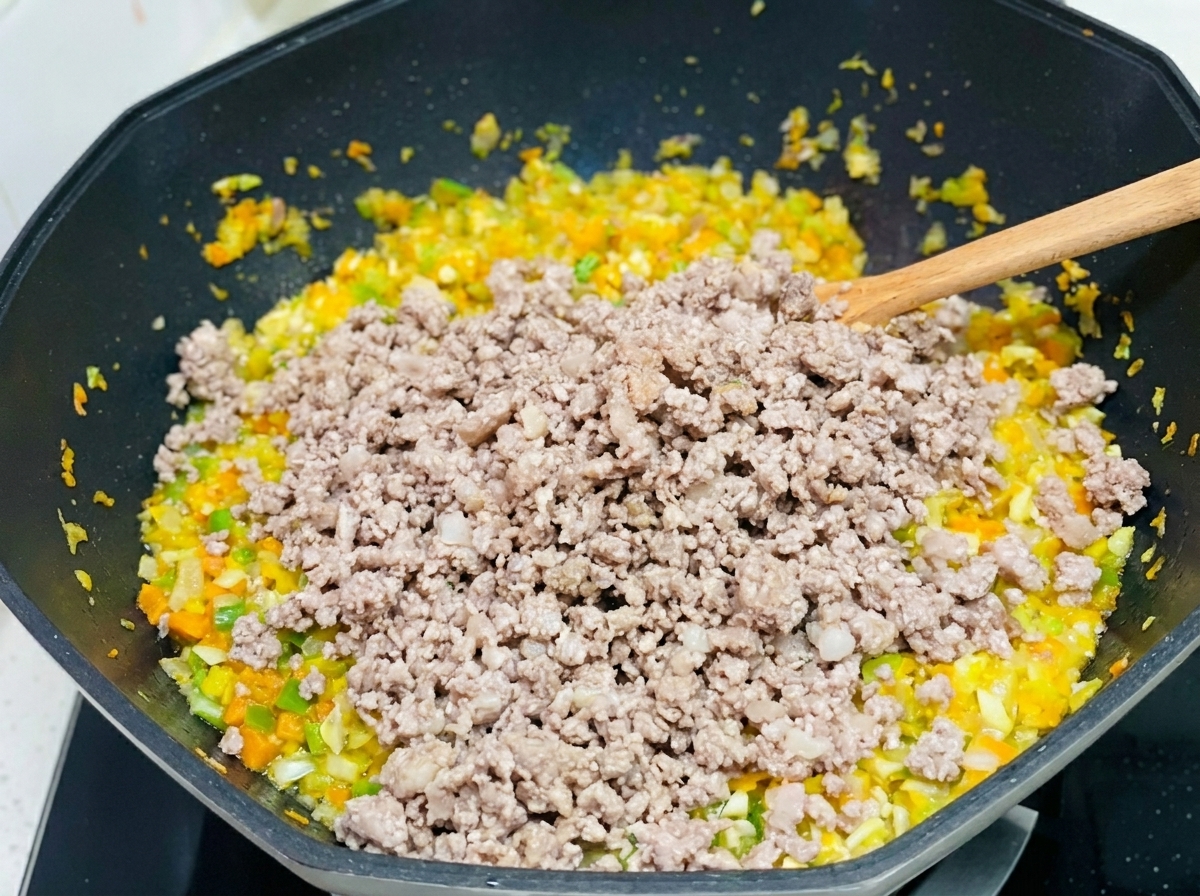 炒めた野菜に焼いたひき肉を戻し入れている様子。