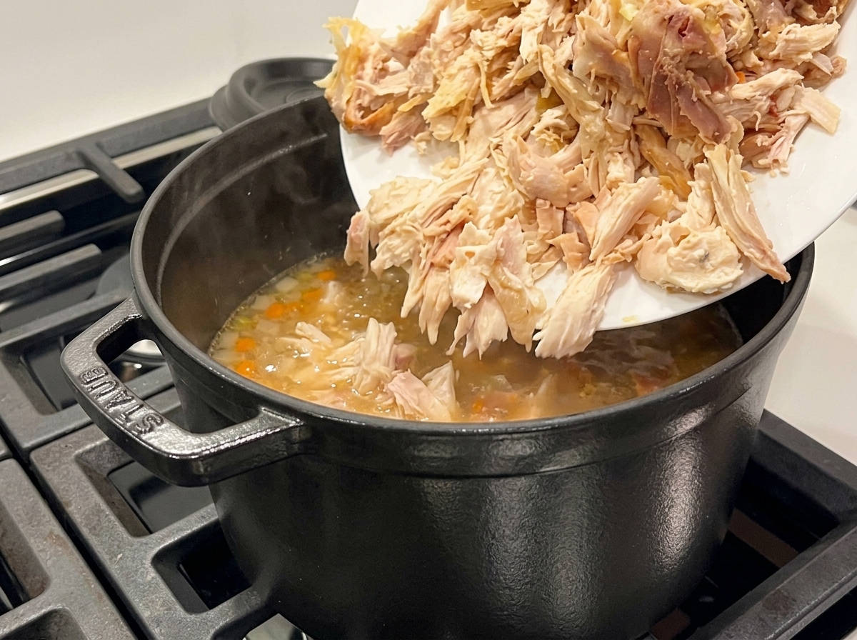 スープにほぐした鶏肉を加える様子。