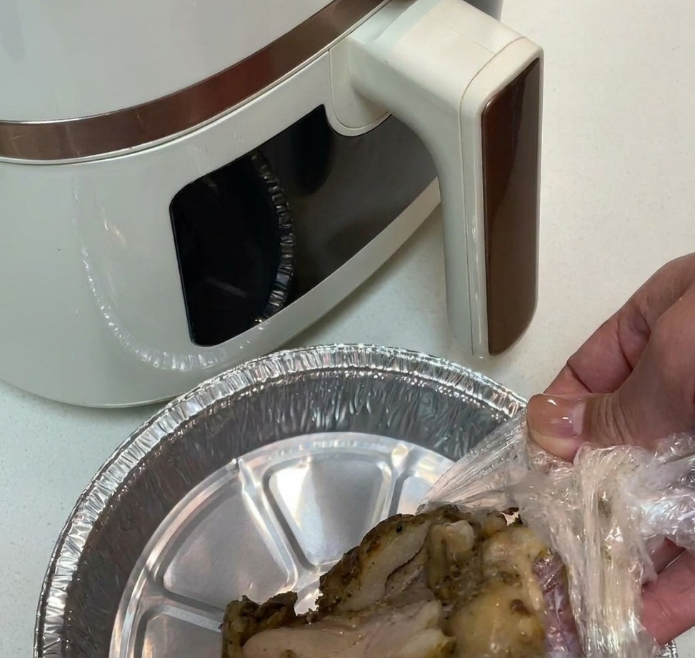 アルミホイルを敷いたエアフライヤーバスケットに鶏肉を並べる様子。