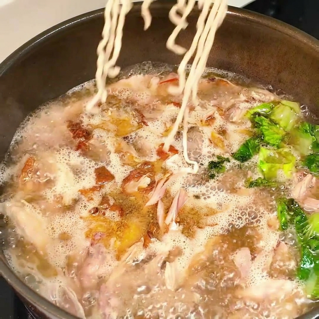 ぐつぐつと煮えるスープの中に、ウェーブ麺を入れて茹でている様子。