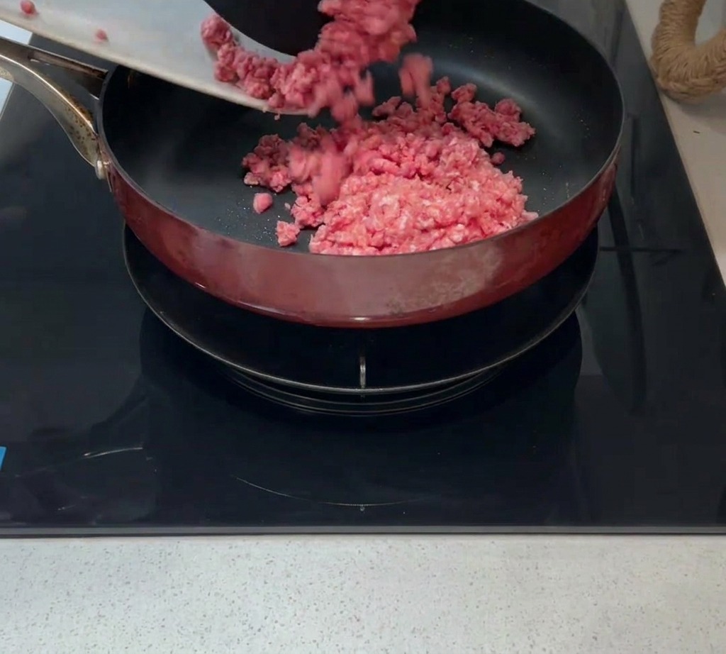 熱したフライパンの油にひき肉を入れている様子。