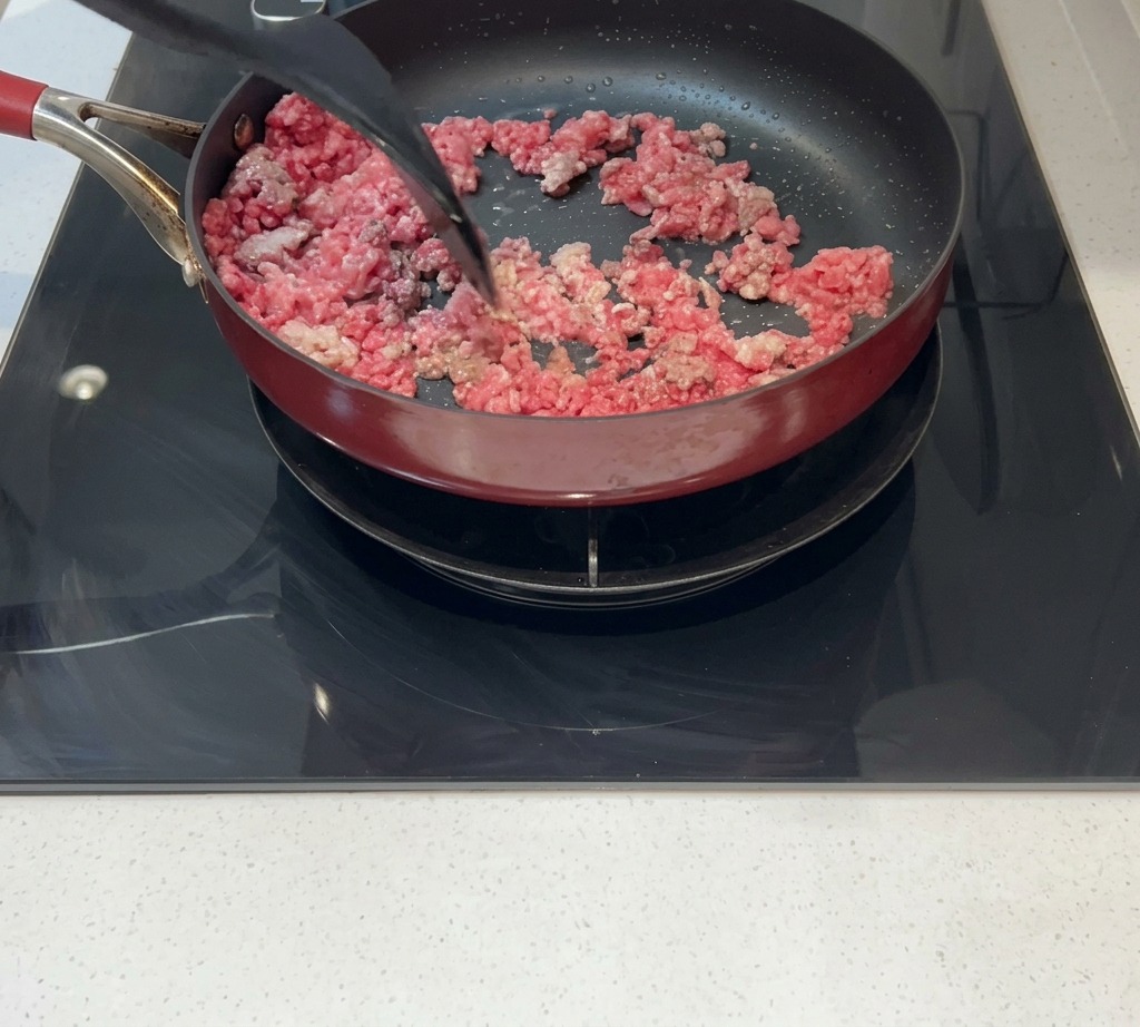 ヘラでほぐしながら、肉をしっかり焼き色をつけている様子。