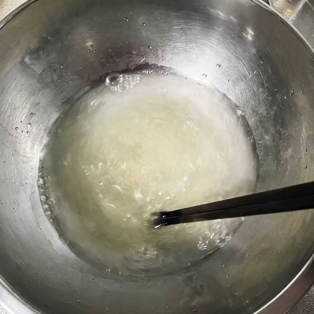 ボウルに入った水にイーストと塩を入れ、箸で混ぜ合わせている様子。