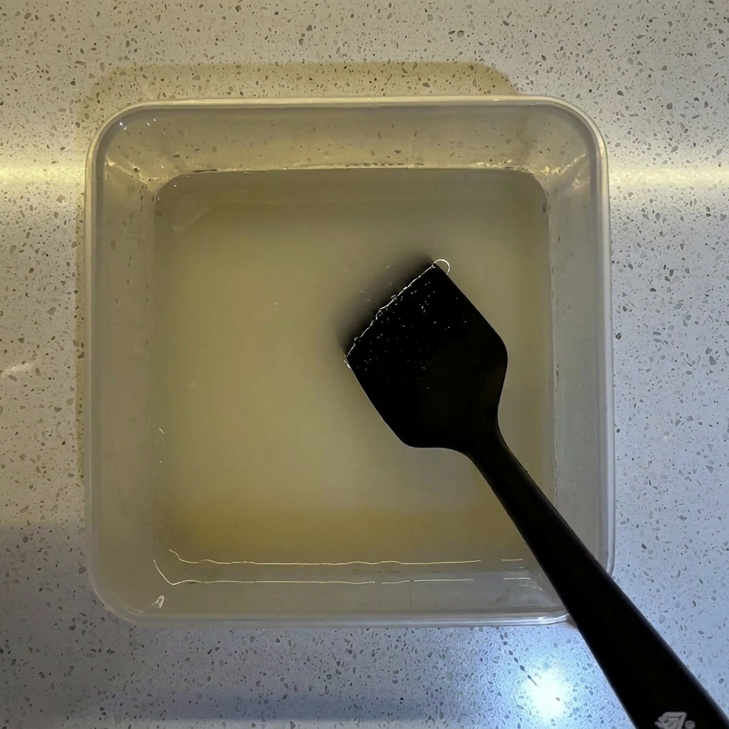 イースト液が入った透明な容器に、小麦粉を注ぎ入れている様子。