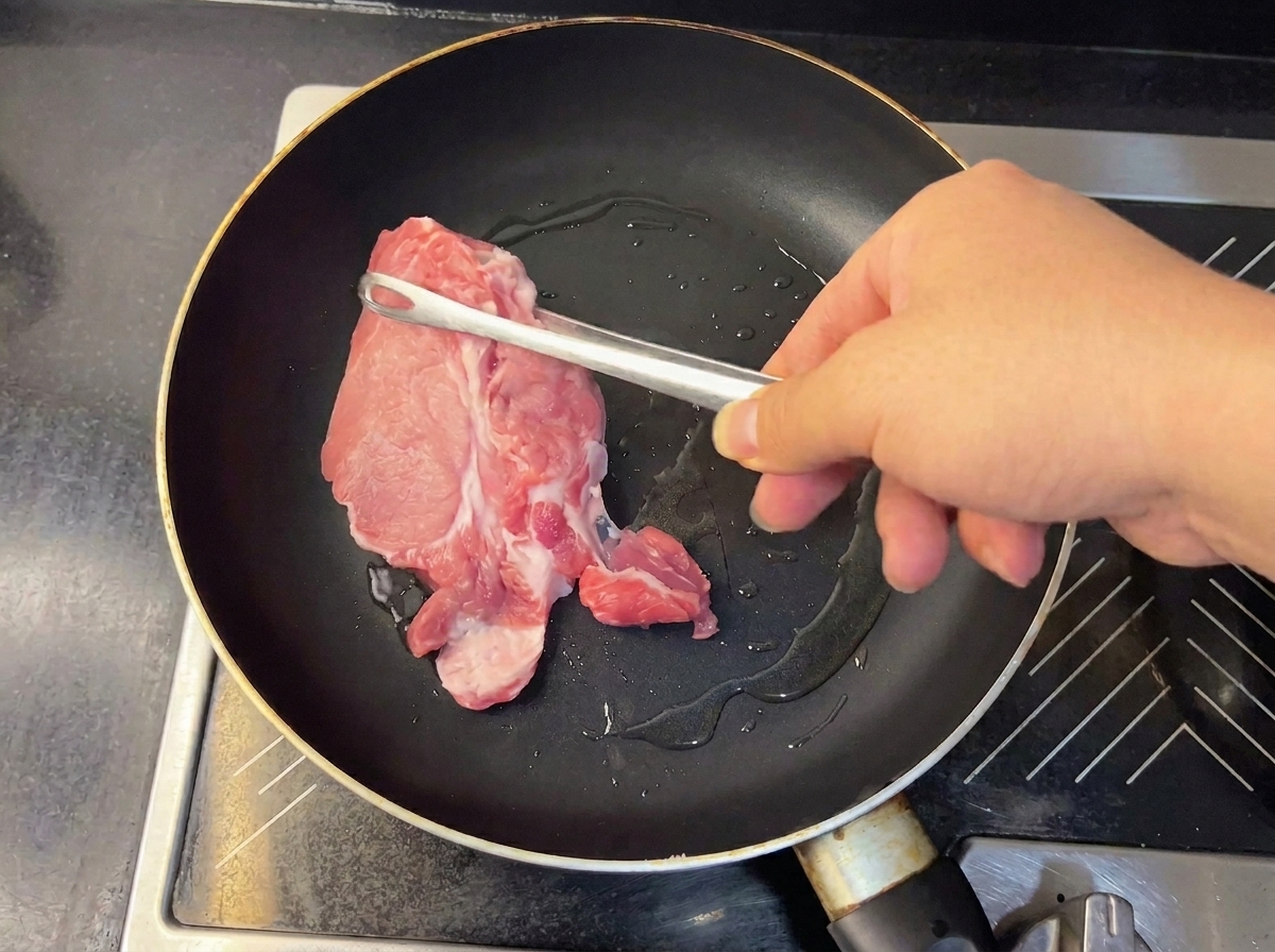 トングで取り出される柔らかそうな煮豚。