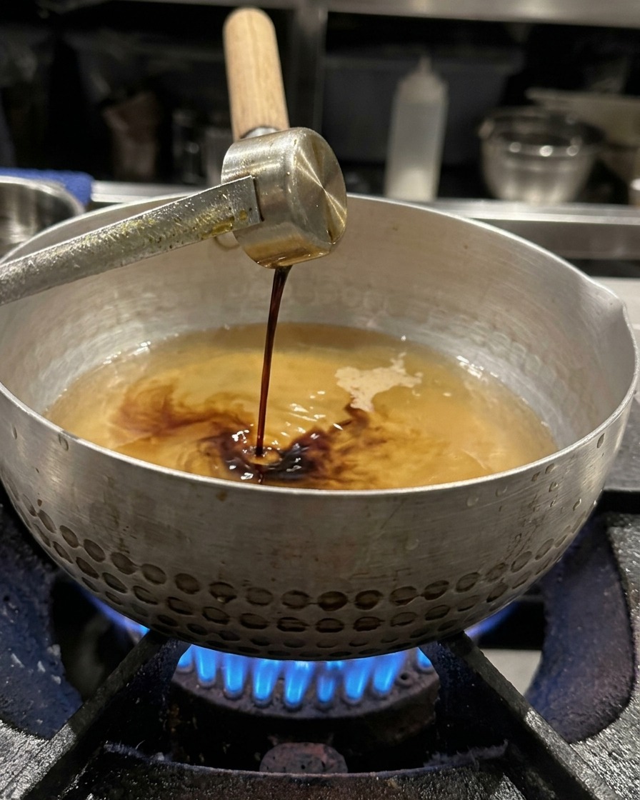 お玉で計った醤油を、スープに加えようとしている様子。