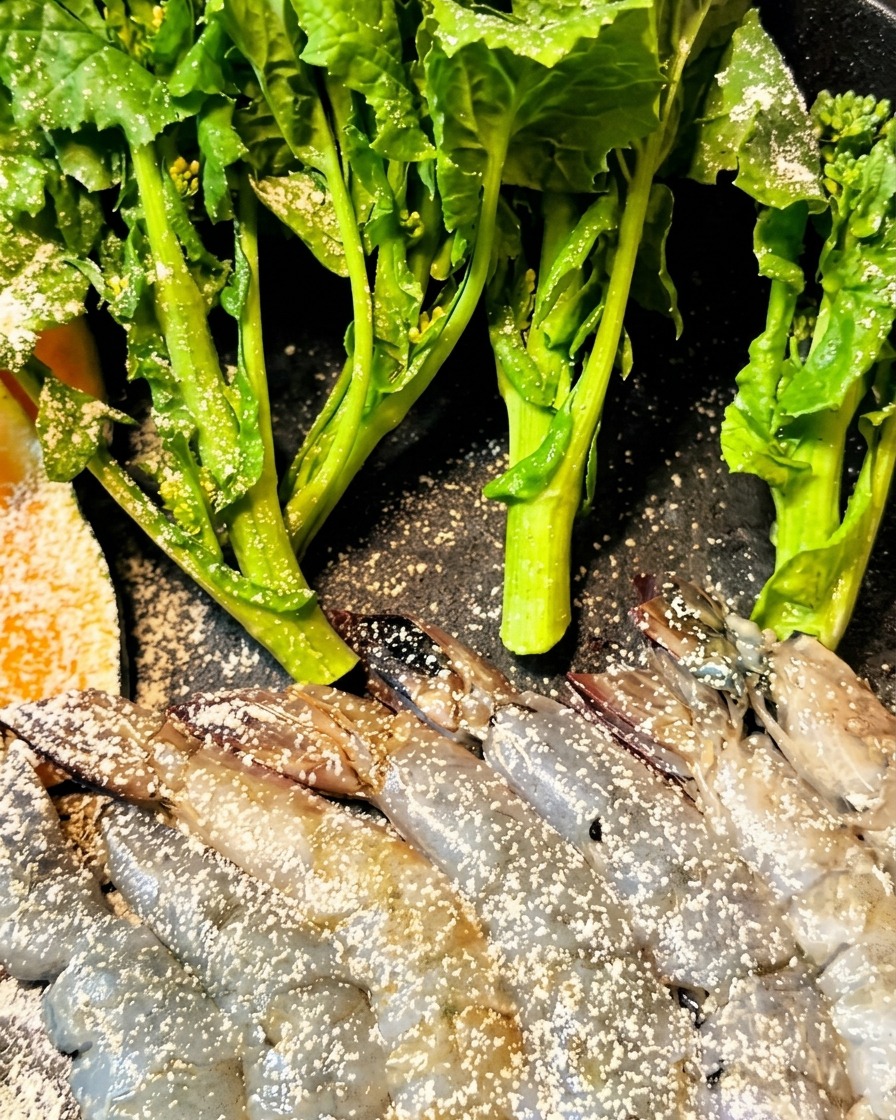 海老と野菜に衣をつけて油で揚げている様子。