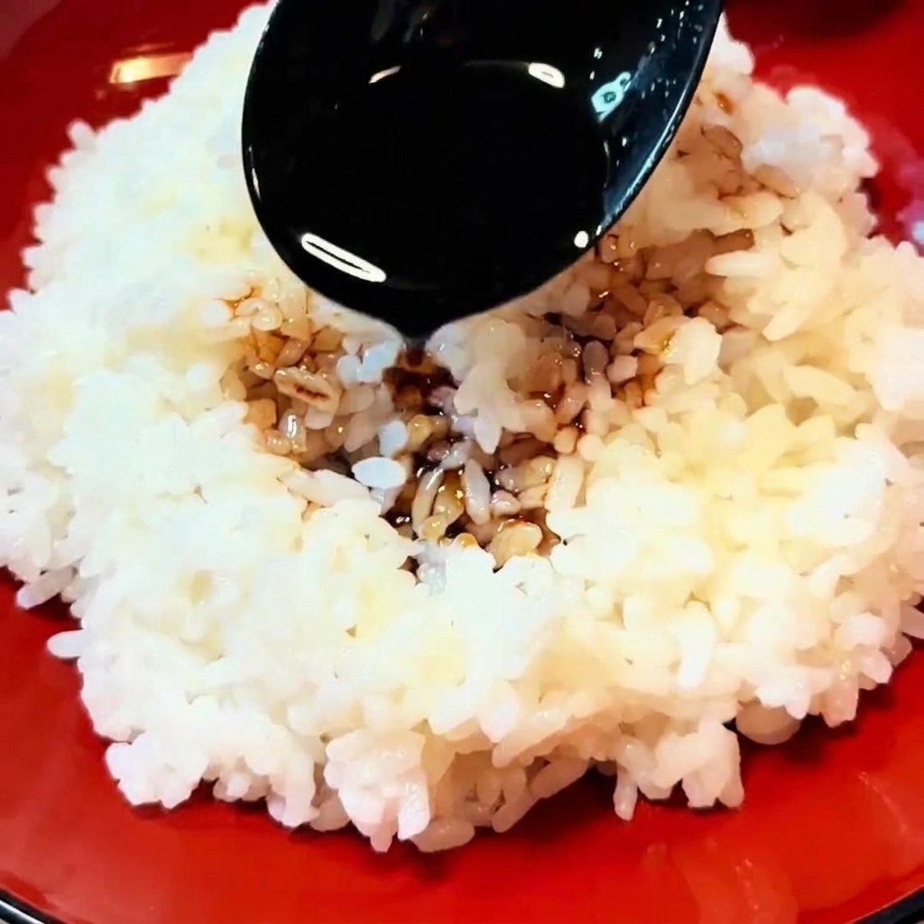 炊きたてのご飯にタレをかけている様子。