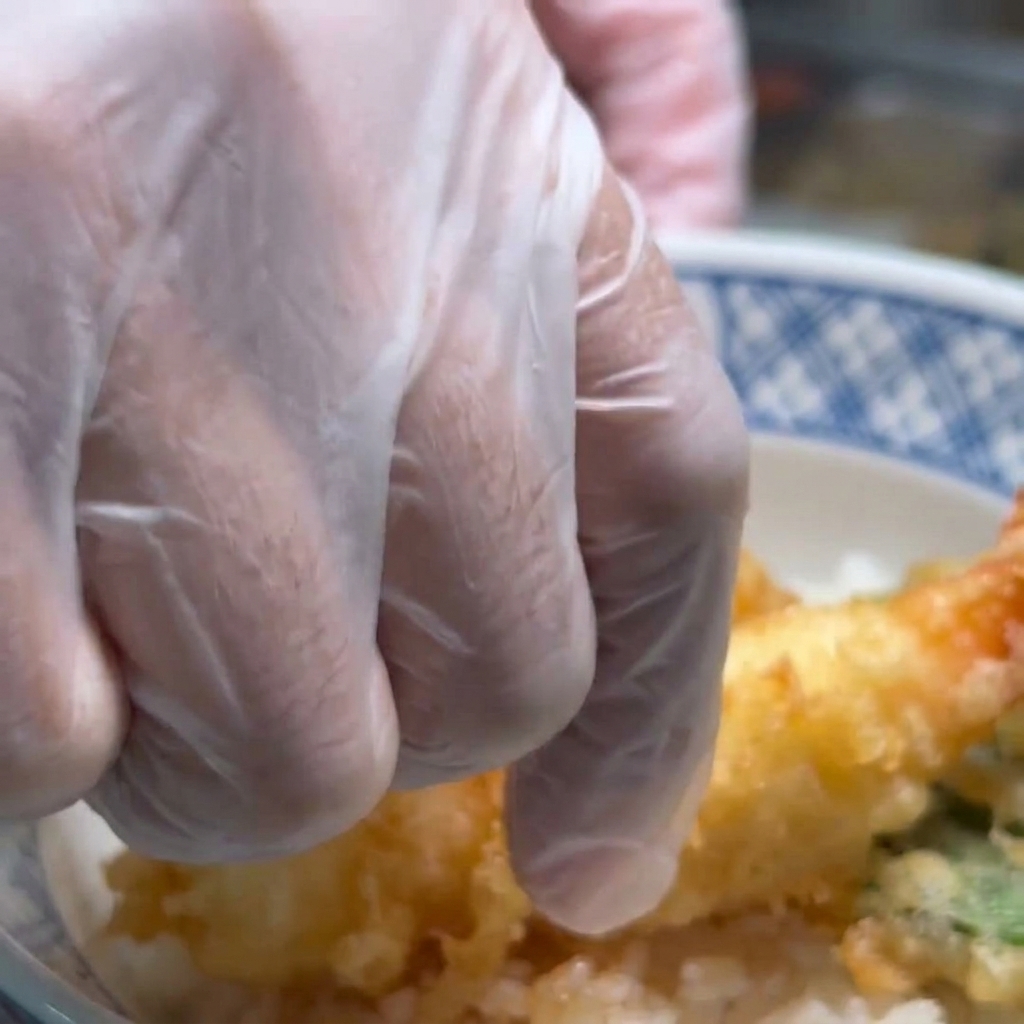 ご飯の上に揚げたての海老天を並べ、盛り付けている様子。