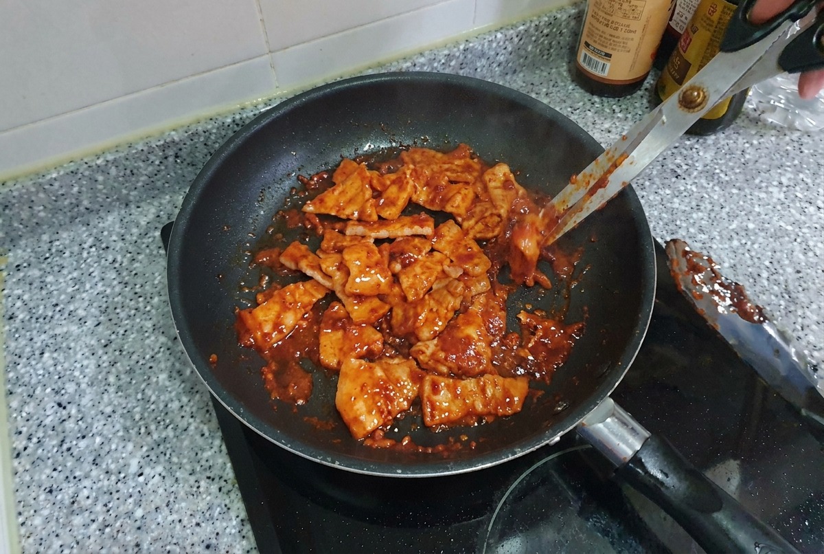 一口大に切ったピリ辛の豚バラ肉をフライパンの中で炒め合わせ、艶やかにカリッと焼き上がっている様子