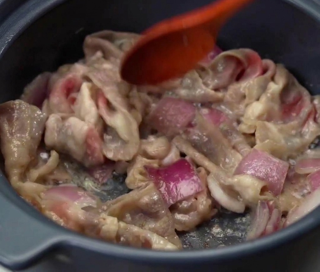 鍋の中で牛肉と赤たまねぎを一緒に炒め、お肉全体に火が通って焼き色がついている様子。
