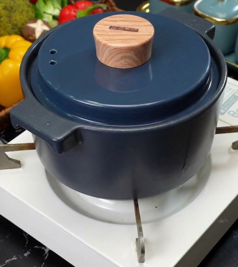 白い卓上コンロの上に置かれた、木目調の蓋がついたおしゃれなブルーのセラミック鍋の様子。