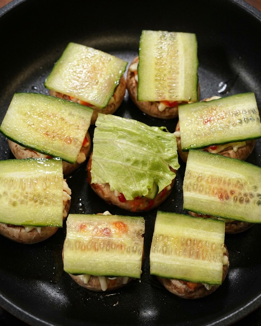 黒いスキレットの中で、きゅうりの上にさらにみずみずしいグリーンレタスの葉を重ねて層を作っている様子