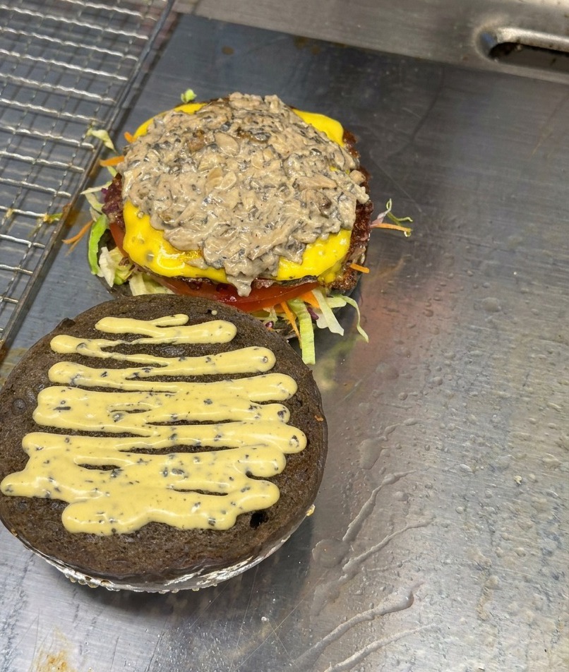 チーズとソースがのったパティの上に、スライスしてソテーされたマッシュルームがたっぷりと積み重なっている様子。