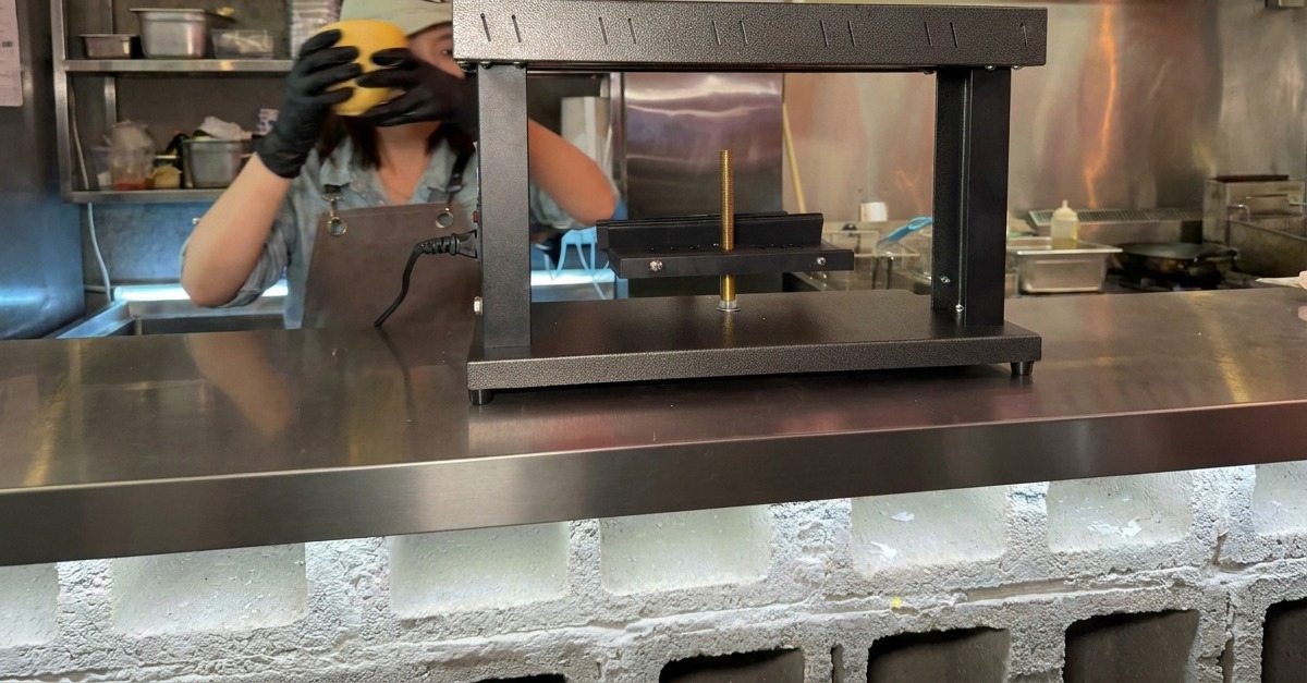専用のラクレットヒーターの台座に、半円状のラクレットチーズをセットする様子。