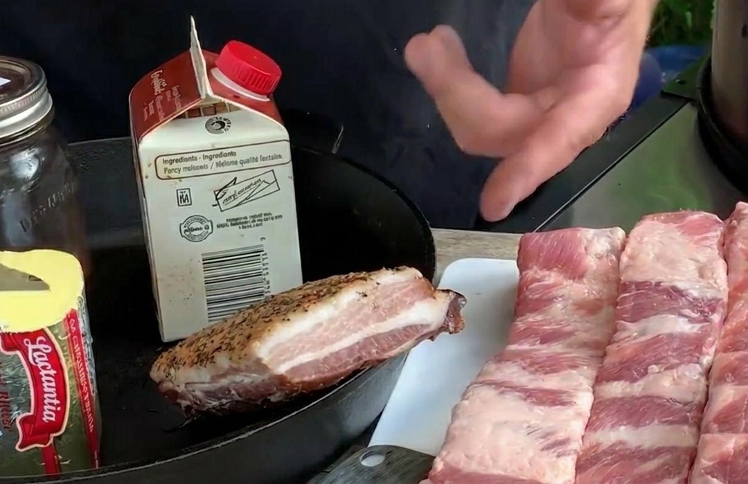 白いまな板の上に並べられた生の長細いポークリブと、バターや新鮮なブルーベリーなどの食材。
