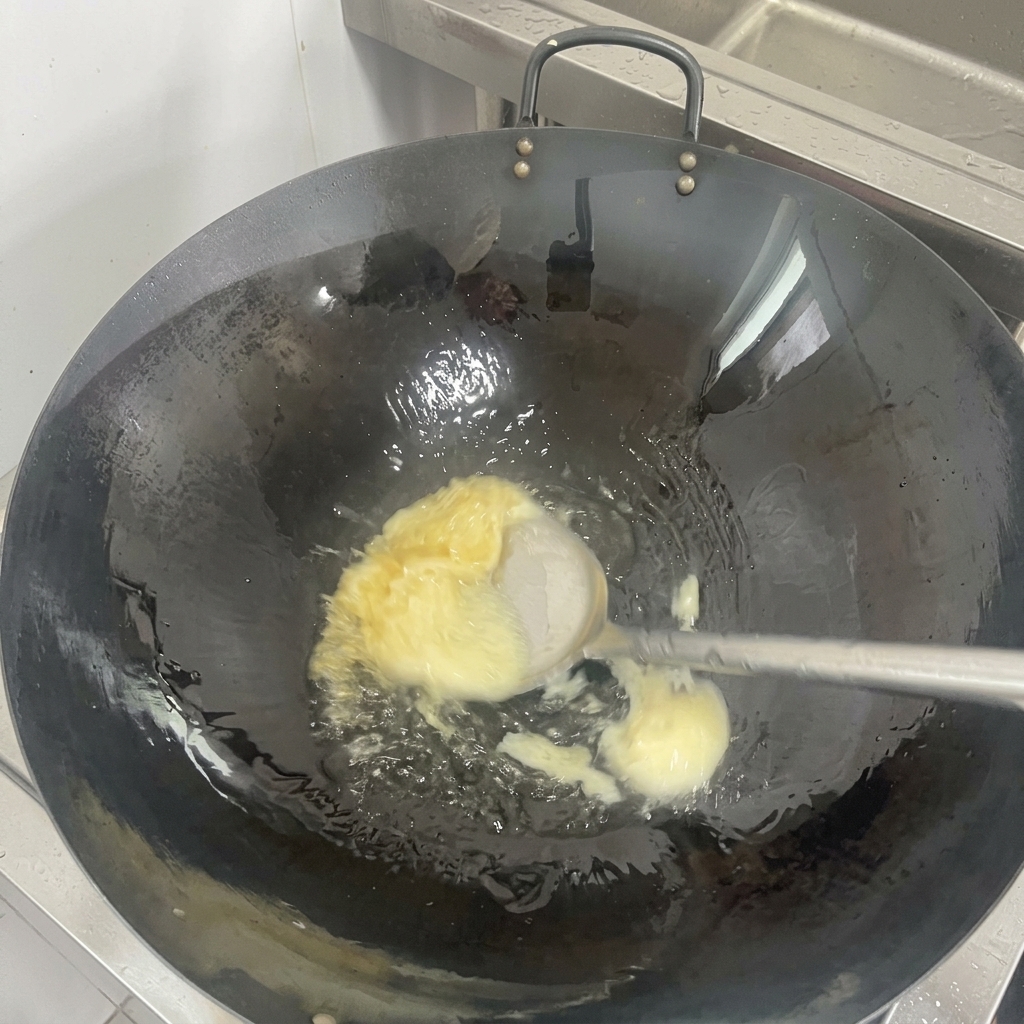使い込まれた黒い中華鍋の底で、白い固形ラードが溶けて透明な油に変わっていく様子。