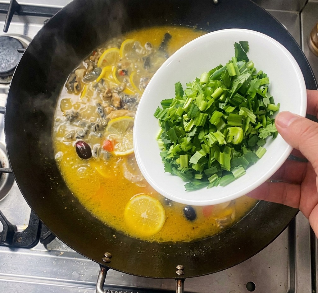 鶏肉とレモンスライスが入って沸騰している中華鍋に、白いボウルから刻んだ緑のパクチーを散らし入れている手。