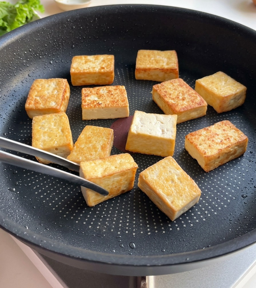フライパンの中の豆腐の表面が、深みのあるきれいな狐色に焼き上がっている様子。