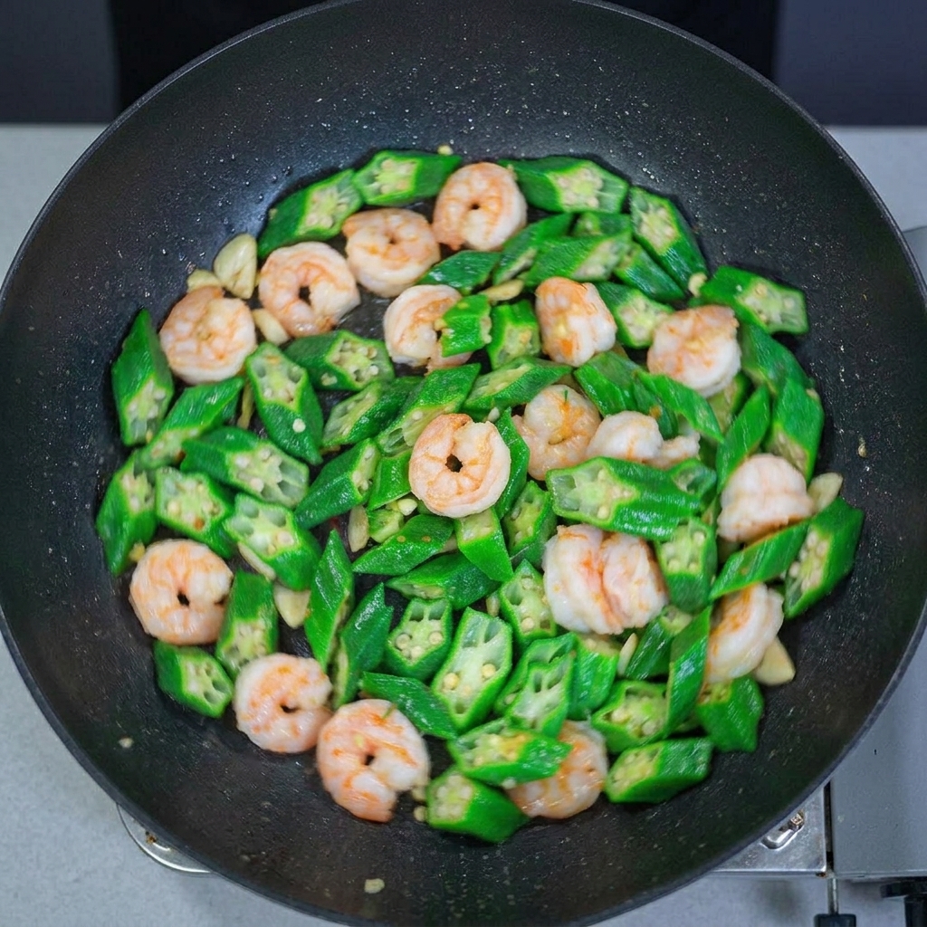 中華鍋の中のオクラとエビの炒め物を上から見た様子。食材が均一に混ざり合い、艶やかに仕上がっています。