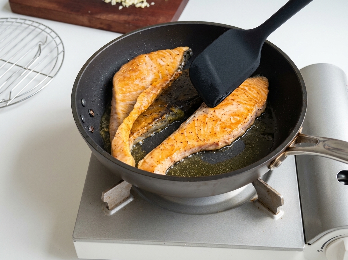 フライパンでサーモンを焼いている様子。こんがりとした焼き色とパリッとした皮が見える