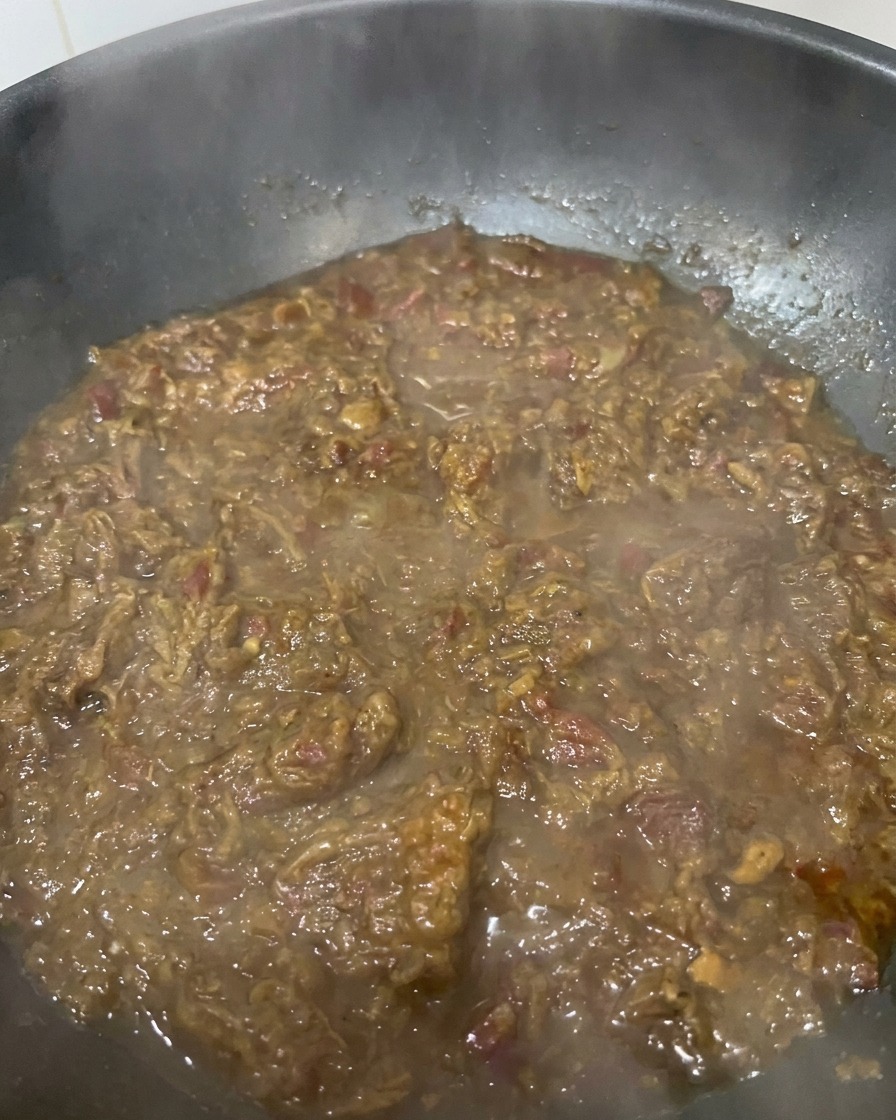 フライパンの中で、濃厚なマホガニー色に変化し、ジャムのようになった玉ねぎと牛肉のソースがコトコト煮詰まっているアップ